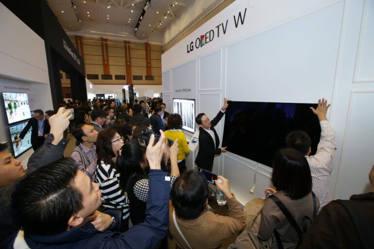 The wallpaper thin LG Signature OLED W being mounted by magnetic installation on a wall